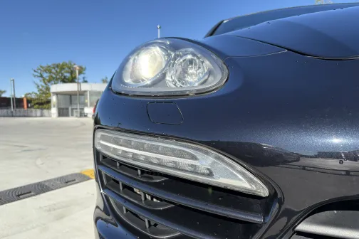 Automobiļa priek&scaron;puses tuvums, spīdīga melna krāsa saulainā dienā.