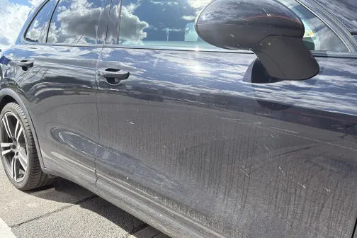 Netīrs melns auto, atspīd debesis.