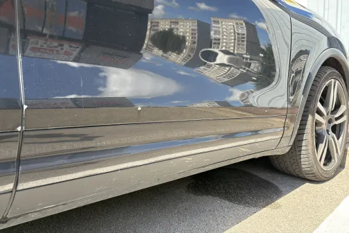 Spīdīgs auto durvis ar pilsētas ēku atspulgu.