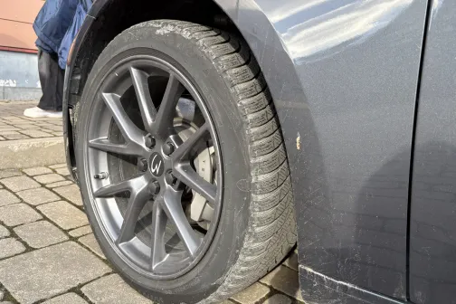 Tum&scaron;a automa&scaron;īna ar sudraba diskiem uz bruģa.