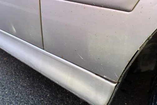 Netīra automa&scaron;īnas durvju apak&scaron;daļa ar skrāpējumiem.