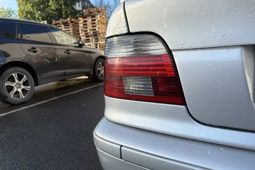 Pelēka automa&scaron;īna stāvvietā ar slapju virsmu.