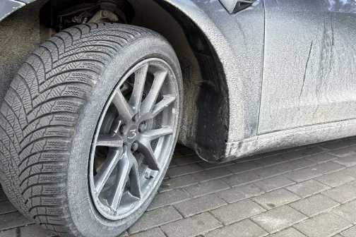 Netīra automa&scaron;īnas riepa un virsbūve uz bruģēta ceļa.