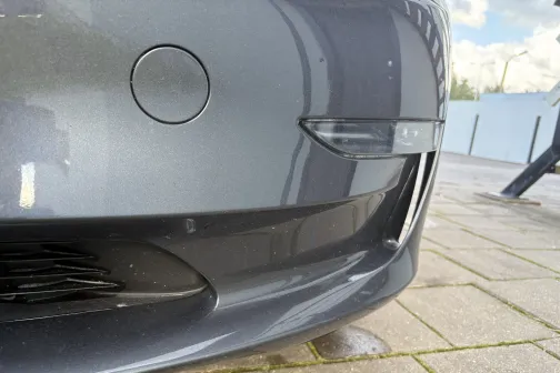 Automa&scaron;īnas priek&scaron;ējais bamperis tuvplānā uz betona seguma.