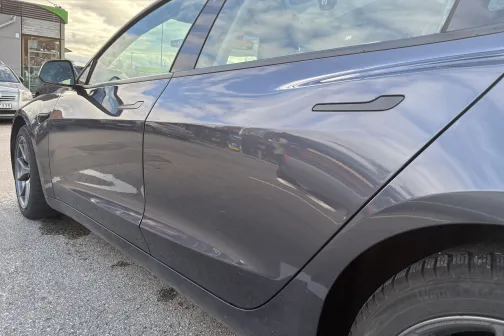 Spīdīga pelēka automa&scaron;īna, mākoņainas debesis fonā.