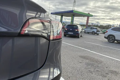 Melna automa&scaron;īna autostāvvietā, fonā redzami citi auto.