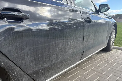 Netīra melna automa&scaron;īna uz bruģēta laukuma.