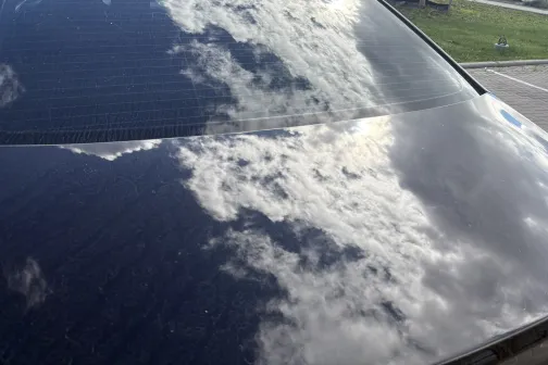 Tīra automa&scaron;īnas virsma atspoguļo mākoņus debesīs.