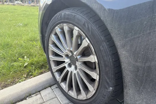 Automa&scaron;īnas netīrs priek&scaron;ējais ritenis uz ietves fona.