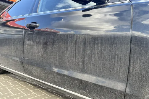 Netīrs melns auto, durvis ar svītrām.