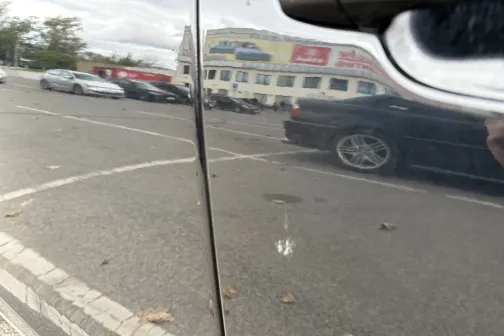 Automa&scaron;īnas durvju atspulgs stāvlaukumā.