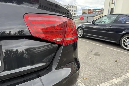 Melnas automa&scaron;īnas aizmugure stāvlaukumā, fokusā sarkanā lampa.