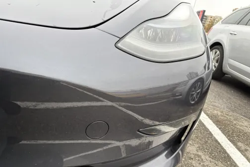 Pelēka automa&scaron;īna tuvplānā autostāvvietā.