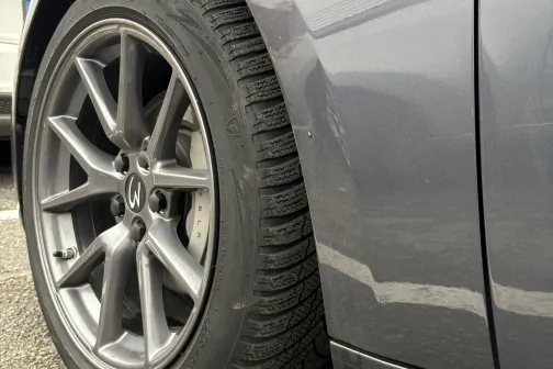 Pelēkas automa&scaron;īnas priek&scaron;ējais ritenis un dubļu sargs.