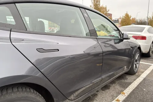 Tum&scaron;s auto novietots stāvlaukumā.