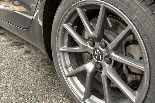 Pelēkas automa&scaron;īnas aizmugurējais ritenis uz asfalta.