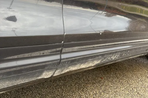 Netīrs auto sāns, redzami dubļi un netīrumi pie durvju apak&scaron;ējās malas.