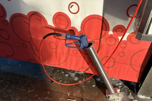 Mazgā&scaron;anas stacija ar zilu putu mazgā&scaron;anas pistoli.