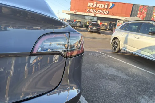 Automa&scaron;īnas aizmugure autostāvvietā, fonā veikals.