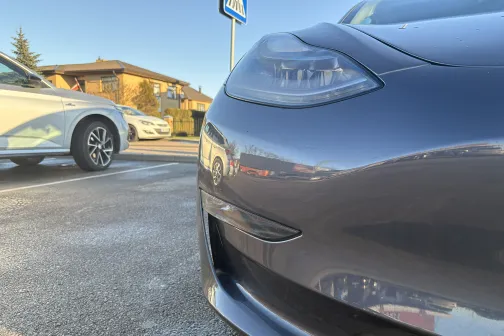 Automa&scaron;īnas priek&scaron;a saulainā dienā, fonā vēl viena automa&scaron;īna.