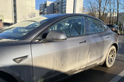 Netīrs sudrabkrāsas auto saulainā stāvvietā.