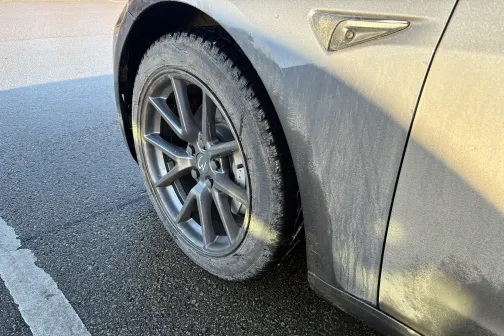 Netīrs automa&scaron;īnas ritenis uz asfalta.