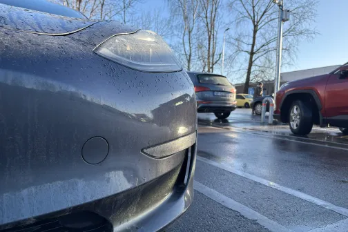 Automa&scaron;īnas priek&scaron;a autostāvvietā, mitrs asfalts.