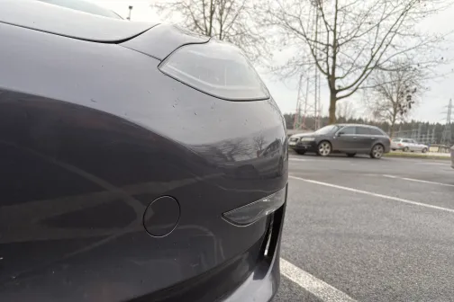 Melna automa&scaron;īna stāvvietā, redzams priek&scaron;ējais lukturis.