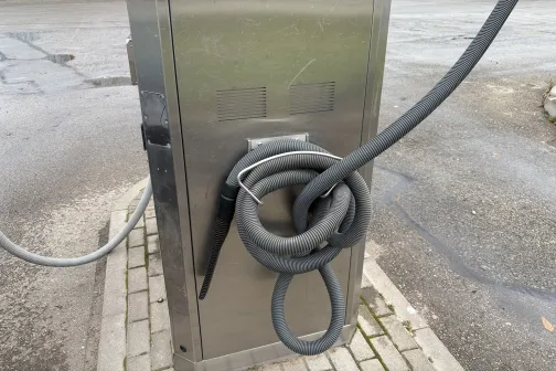 Metāla putekļsūcējs ar &scaron;ļūtenēm autostāvvietā.