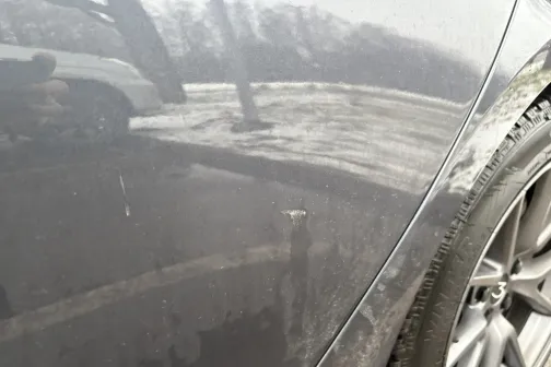 Netīra automa&scaron;īnas sānu daļa ar riepu tuvplānā.