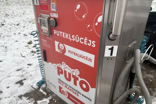 Putekļu sūcējs ar sarkanām uzlīmēm pie mazgātavas.