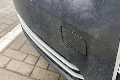 Netīrs auto bamperis uz bruģēta ceļa.