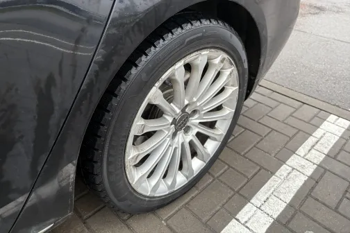 Pelēka automa&scaron;īna ar tīru disku un riepu uz bruģēta laukuma.