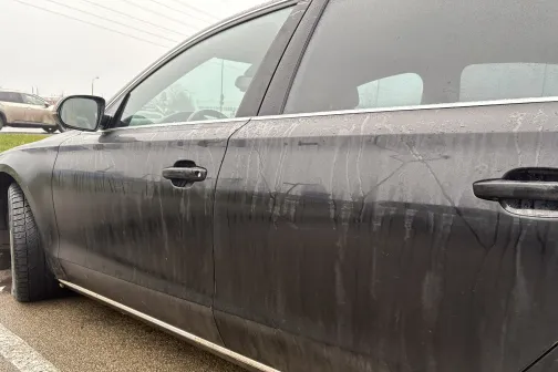 Netīrs tum&scaron;as krāsas auto sānskats stāvlaukumā.