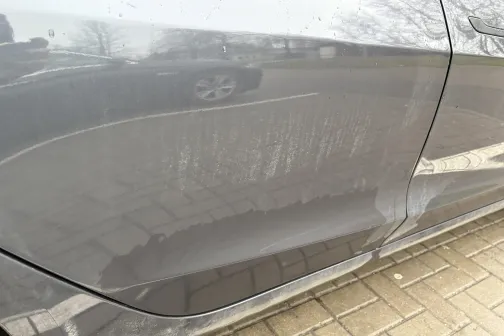 Netīrs sudraba auto sāns uz bruģa fona.