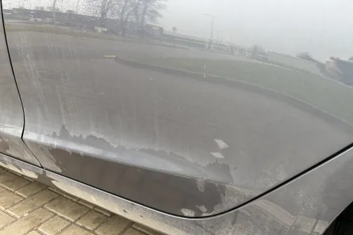 Netīrs auto sāns uz ceļa fona.