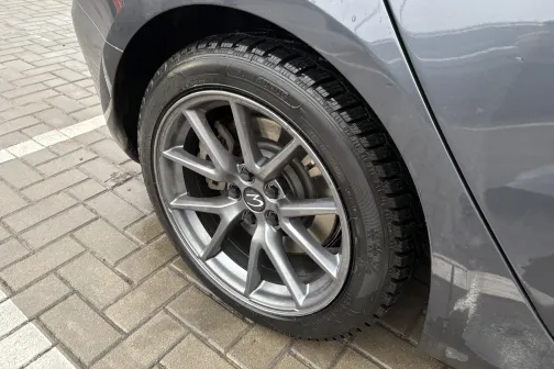 Pelēka automa&scaron;īnas riepa un disks uz bruģa.