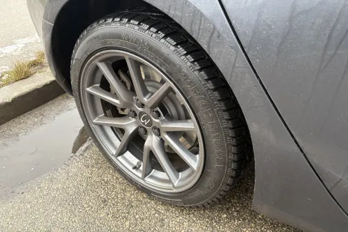 Auto aizmugurējais ritenis ar mitru riepu uz ielas malas.