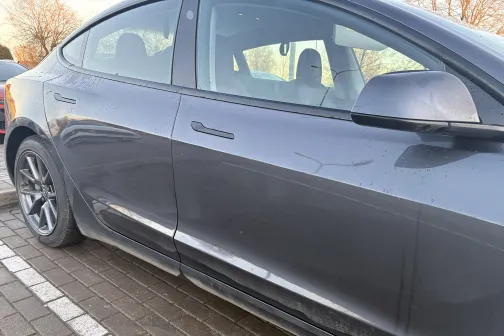 Melnas automa&scaron;īnas sānskats uz bruģēta ceļa.