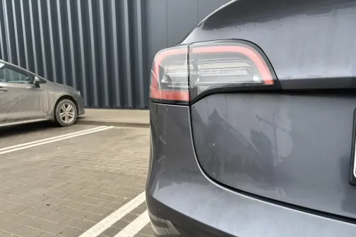 Pelēkas automa&scaron;īnas aizmugure pie autostāvvietas līnijas.