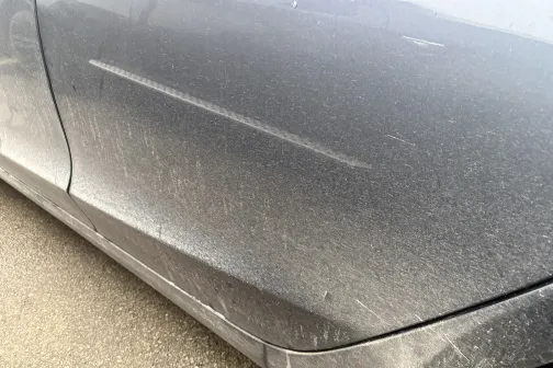 Netīrs pelēkas automa&scaron;īnas sāns ar putekļiem.