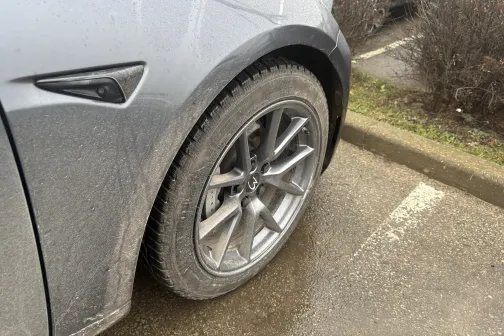 Netīrs sudraba automa&scaron;īnas ritenis stāvvietā.