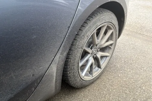 Auto netīrs aizmugures ritenis uz asfaltēta ceļa.