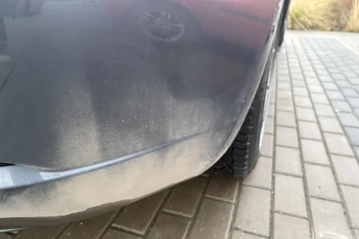 Netīrs automa&scaron;īnas bamperis uz bruģētas ielas.