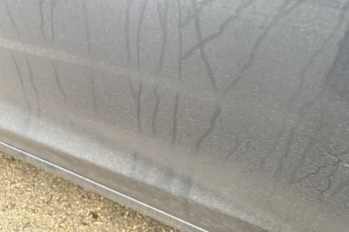 Netīra automa&scaron;īnas sānu virsma ar ūdens pilēm.