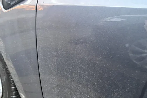 Netīras automa&scaron;īnas durvis ar redzamiem netīrumiem un putekļiem.