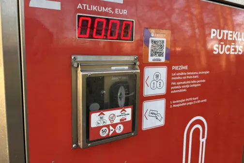 Sarkanā automazgātavas maksājumu un putekļu sūcēja paneļa displejs ar norādēm.