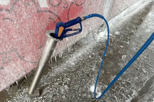 Putu mazgā&scaron;anas pistole pie sasalu&scaron;as automazgātavas sienas.