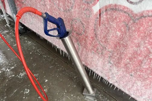 Augstspiediena mazgā&scaron;anas pistole pie sienas, ledus fonā.