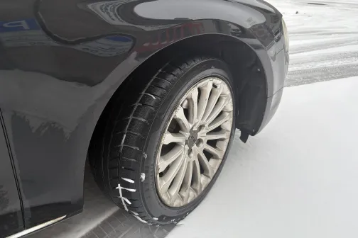 Tum&scaron;as krāsas automa&scaron;īnas priek&scaron;ējais ritenis sniegā.